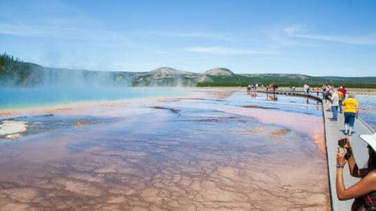 Tourists Capture Photos Of The Rainbow Colors Of The Grand Prismatic Spring In Yellowstone National Park
