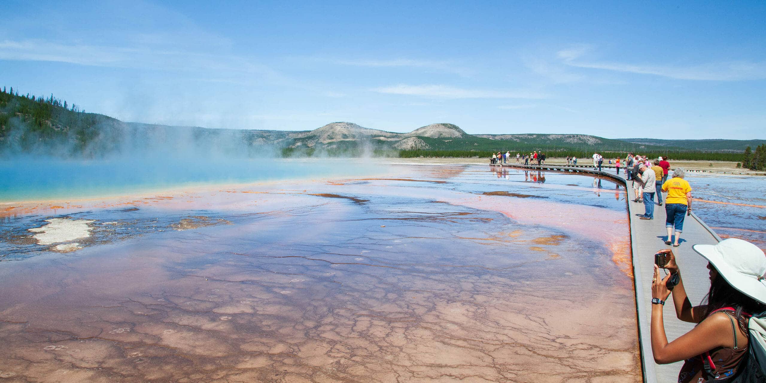 Tourists Capture Photos Of The Rainbow Colors Of The Grand Prismatic Spring In Yellowstone National Park