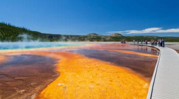 Visitors Stop Along The Wooden Boardwalk To Admire The Vibrant Reds, Greens And Blues Of The Grand Prismatic Spring In Yellowstone National Park