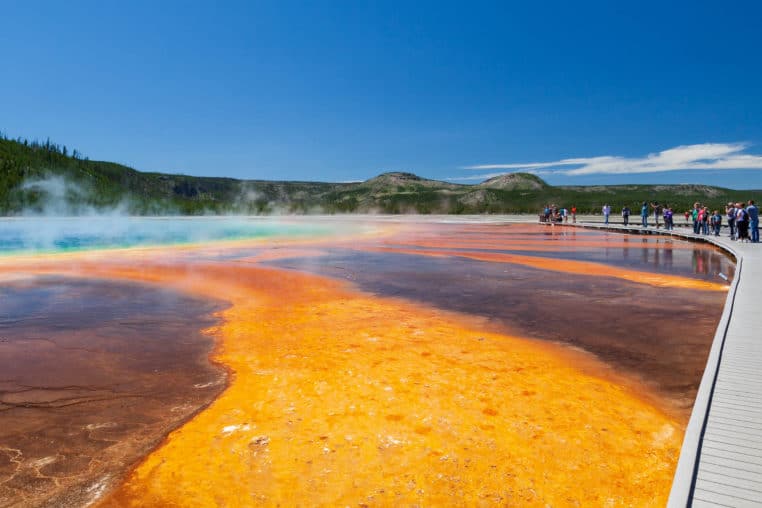 Visitors Stop Along The Wooden Boardwalk To Admire The Vibrant Reds, Greens And Blues Of The Grand Prismatic Spring In Yellowstone National Park