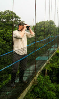 Jason Williams Looks Through Binoculars While On A Wildlife Expedition In Ecuador
