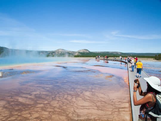 Tourists Capture Photos Of The Rainbow Colors Of The Grand Prismatic Spring In Yellowstone National Park