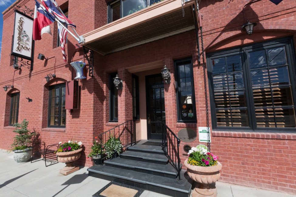The Inviting Entrance To The Chamberlin Inn Features A Brick Facade With Flowers And Front Steps