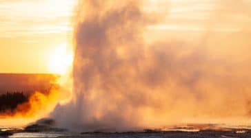 A Geyser Erupts Against the Dusky Backdrop of the Setting Sun in Yellowstone National Park