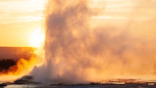 A Geyser Erupts Against the Dusky Backdrop of the Setting Sun in Yellowstone National Park